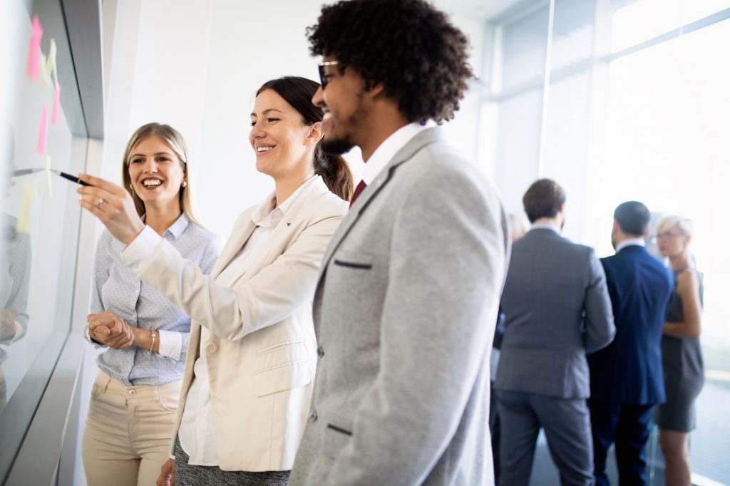 A team of individuals works together in front of a board.