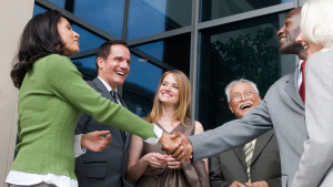 New nonprofit board members smiling and shaking hands as they meet each other for the first time at the door of an office building.